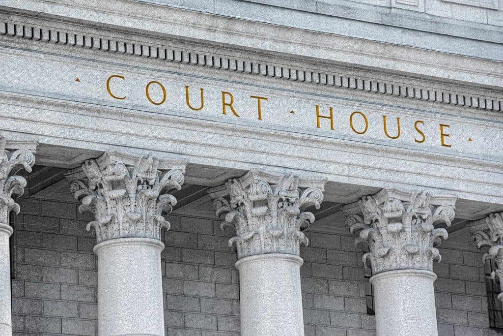 The facade of a courthouse with large columns and the words "Court House" engraved above the entrance in gold lettering.