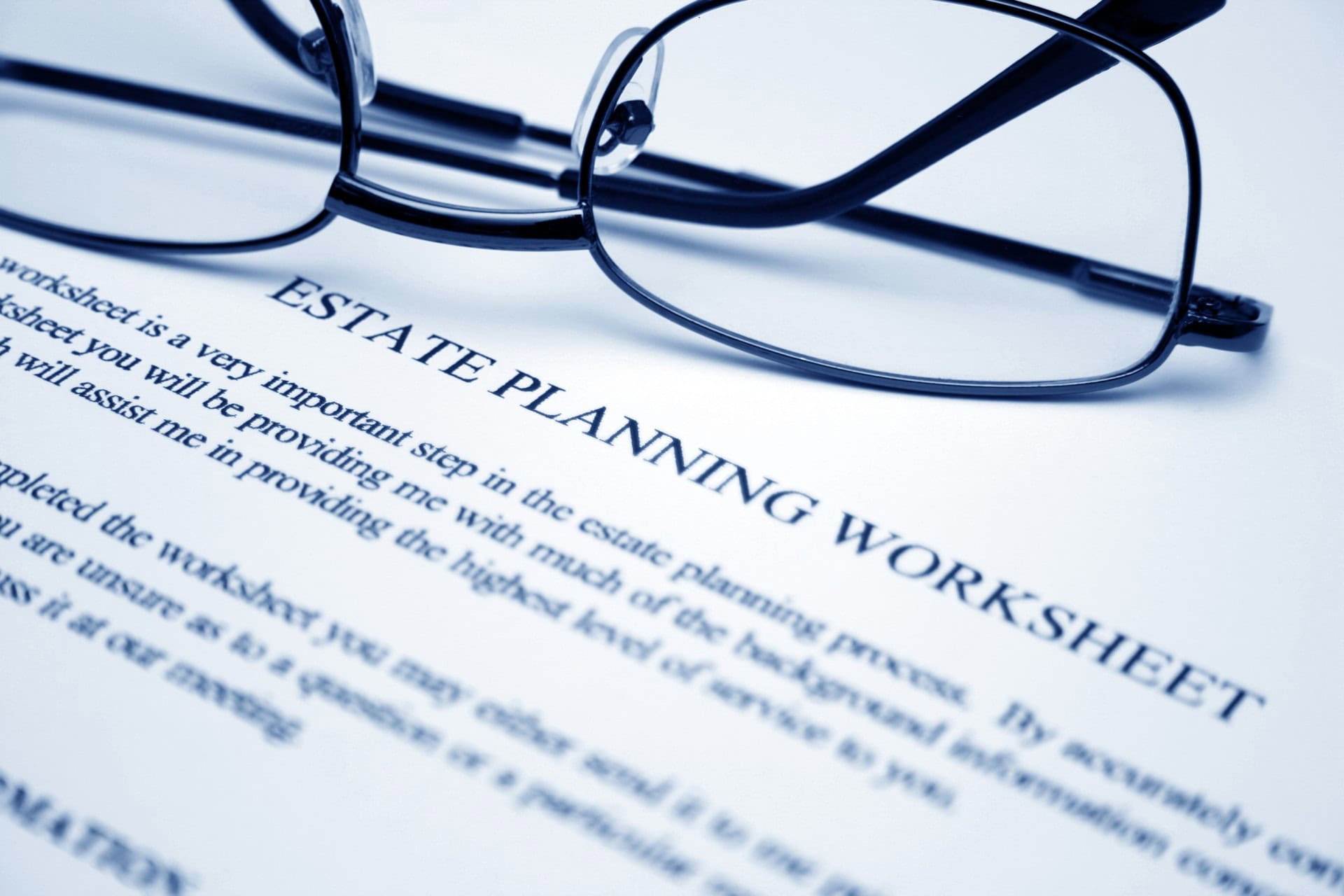 Close-up of eyeglasses resting on a document titled "Estate Planning Worksheet," with text in focus.